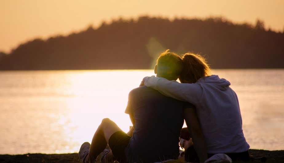 people hugging by sunset over a body of water