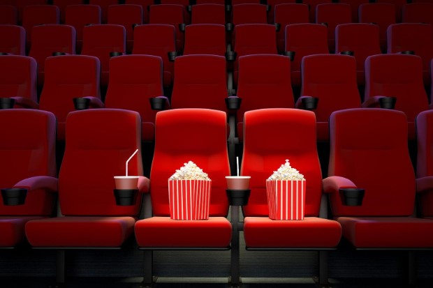 cinema seats with two having popcorn and drinks in them